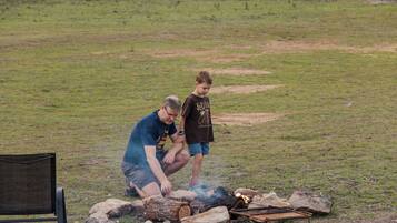 An outdoor setting with a fire pit, rocks, and a chair.
