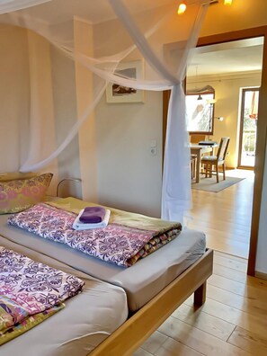 Un dormitorio con dos camas, dosel, zona de comedor y vistas al exterior.