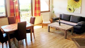 Ein Wohnzimmer mit Esstisch, Stühlen, einer Couch und einem Couchtisch.
