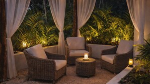 An outdoor seating area with wicker furniture, a round table, and draped curtains. - AJAW Cabana | Jungle, privacy and relaxation near Cancun (Leona Vicario)