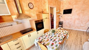 A compact kitchen with a dining area, a clock, and a television. - BILO PESARO MARCELLI - Two-room apartment with a/c just a stone's throw from the sea and the center (Marcelli)