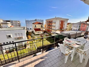 A balcony with a table and chairs, a view of buildings, and a fenced yard. - BILO PESARO MARCELLI - Two-room apartment with a/c just a stone's throw from the sea and the center (Marcelli)