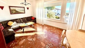 Un salon avec un canapé, une table basse et une vue sur l’extérieur par une fenêtre.