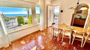 Une pièce comprenant une table à manger, des chaises, de grandes fenêtres offrant une vue et un coin cuisine.