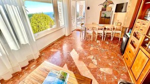 Une pièce spacieuse dotée d’une grande fenêtre, d’un coin repas et d’une cuisine.