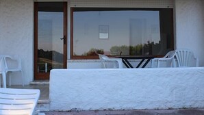 Ein Zimmer mit einer Schiebetür, einem Tisch mit Stühlen und Blick ins Freie.