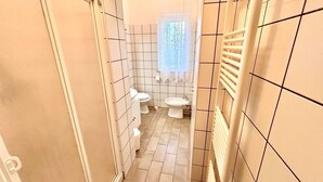 A narrow bathroom with white tiled walls, a radiator, and two toilets. - Delightful cottage with garden and terrace overlooking the sea (Numana)