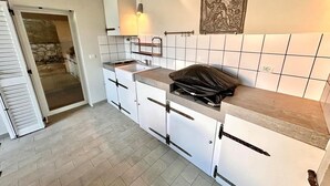 A kitchen with white cabinets, a countertop, a black bag, and a decorative wall piece. - Delightful cottage with garden and terrace overlooking the sea (Numana)