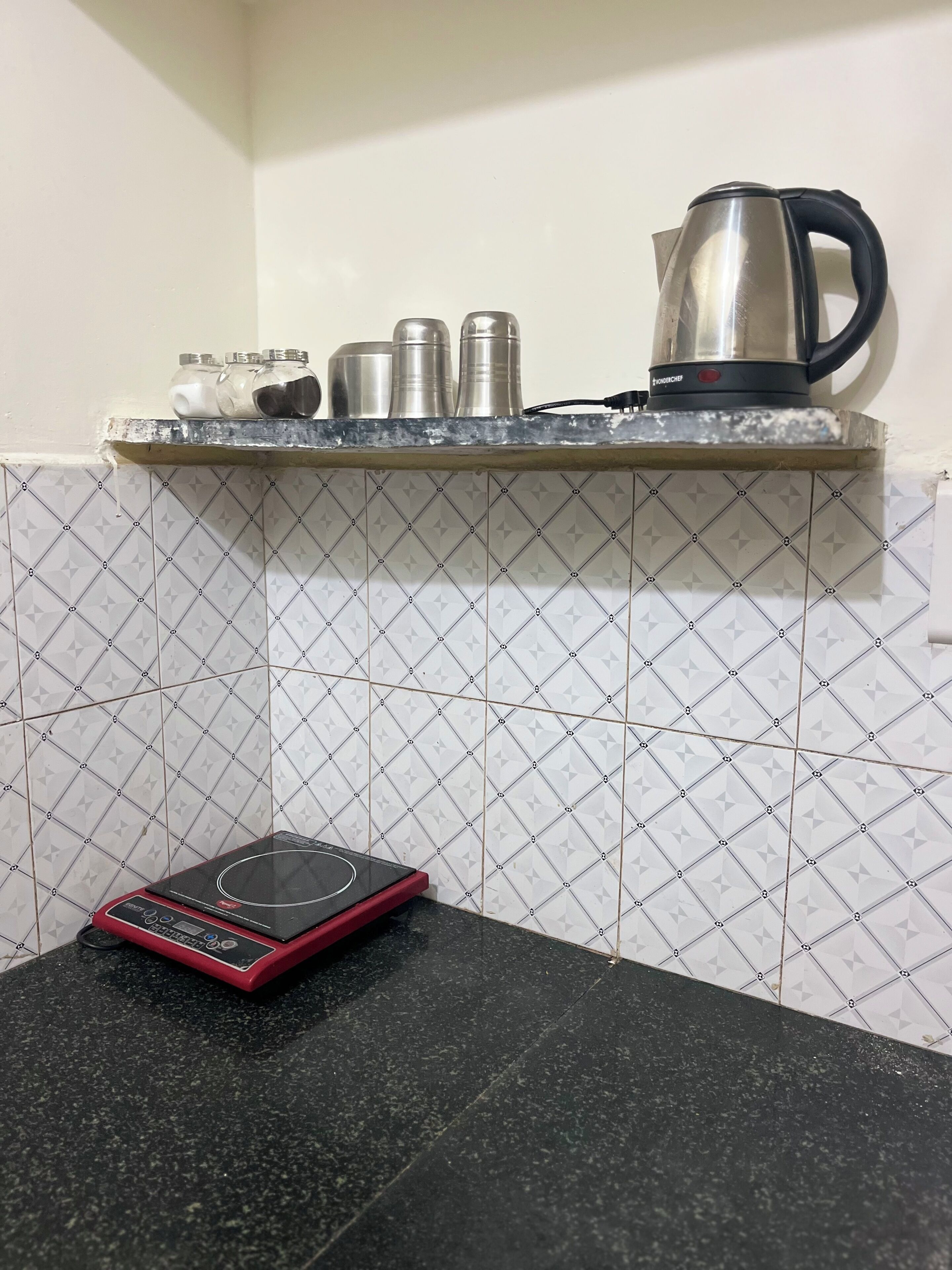 A kitchen with a countertop, a kettle, and a scale.