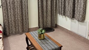 A room with a wooden bench, a potted plant, and patterned curtains. - Tremendous 1-bedroom house in vibrant Bengaluru awaits you (Bengaluru)