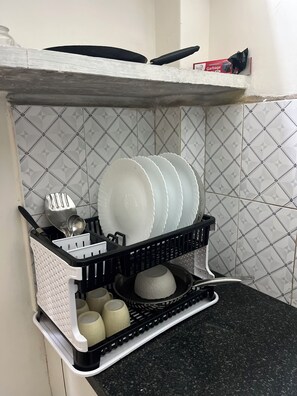A kitchen with a dish rack holding plates, cups, and utensils. - Tremendous 1-bedroom house in vibrant Bengaluru awaits you (Bengaluru)