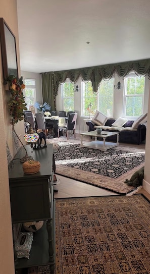 Un salon comprenant un canapé, une table basse, une table à manger avec des chaises et un tapis à motifs.