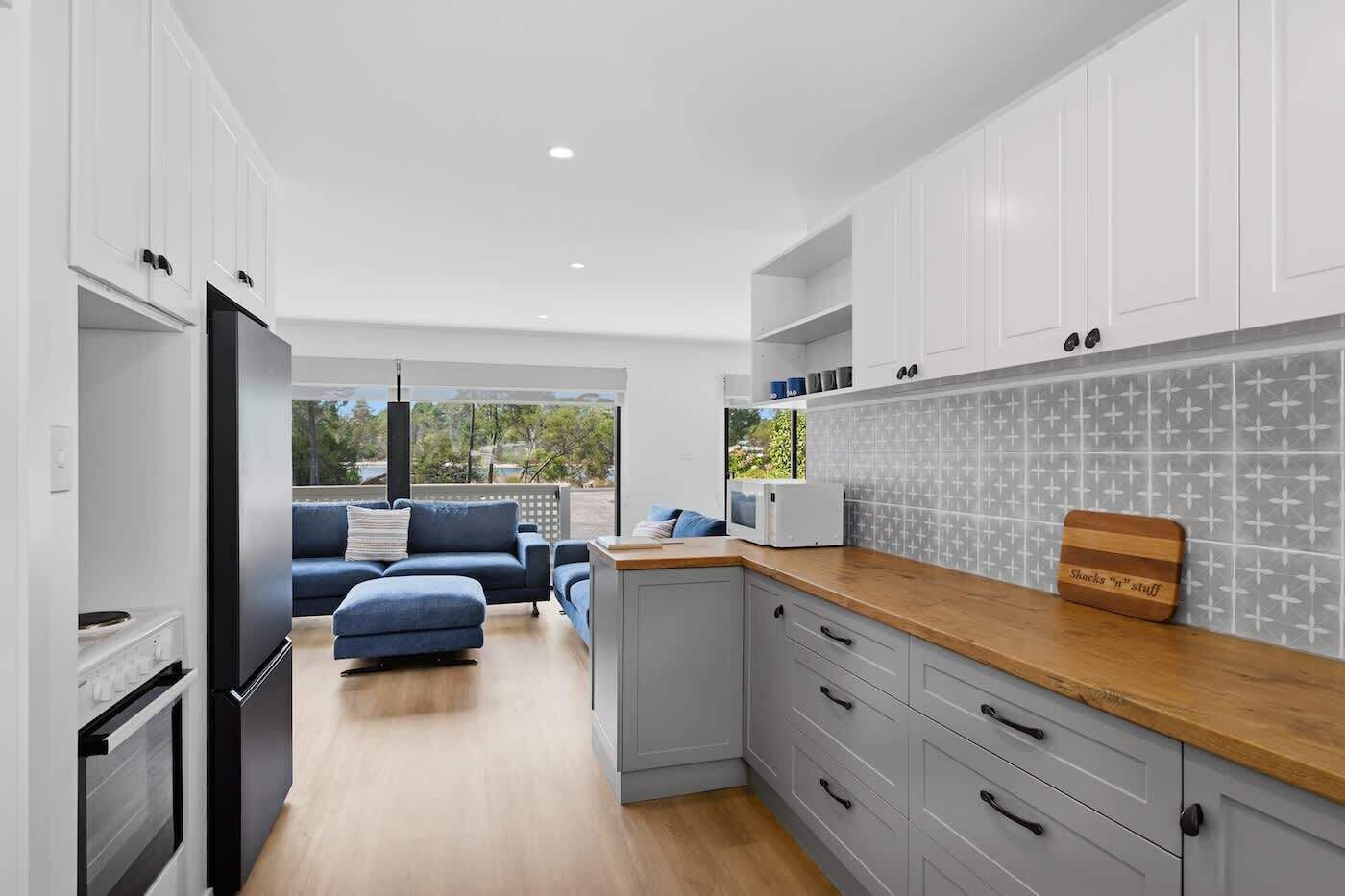 A modern kitchen with grey cabinets, a wooden countertop, and a view to the outdoors.