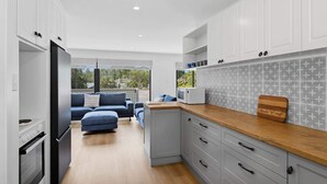 Una cocina moderna con armarios grises, encimera de madera y vistas al exterior.