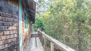Eine Holzterrasse mit Geländer, umgeben von dichtem Grün.