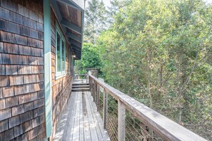 Eine Holzterrasse mit Geländer, umgeben von dichtem Grün.