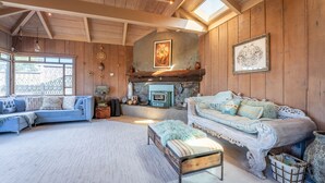 Ein gemütliches Wohnzimmer mit Kamin, zwei Sofas und einem großen Fenster.