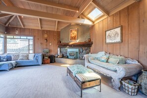 Ein gemütliches Wohnzimmer mit Kamin, zwei Sofas und einem großen Fenster.