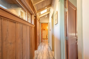 A wooden hallway with a door on the right, a window on the left, and a staircase at the end. - a luxurious and elegantly appointed 4-bed, 4-bath home situated on 1.83 acres (Little River)