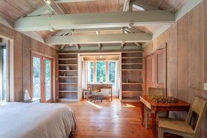 Un interior de madera con cama, escritorio y mesa de ajedrez.