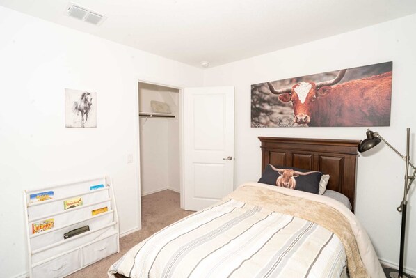 A bedroom with a bed, a closet, a coat rack, and a wall-mounted lamp.