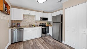 Una cocina moderna con armarios blancos, electrodomésticos de acero inoxidable y piso de madera.