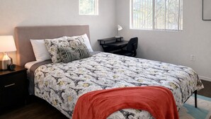 A bedroom with a bed, bedside table, lamp, desk, chair, and two windows. - Cozy 2B2B in Downtown PHX • Near Airport • Perfect Work or Getaway• (Phoenix)