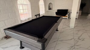 A pool table in a room with white brick walls, a white ceiling, and a marble-tiled floor. - QUINTA ANUBIS (Oaxtepec)