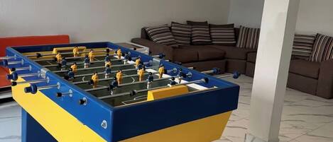 A foosball table in a room with a sofa and a pillar.