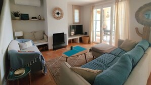 Ein Wohnzimmer mit Sofa, Fernseher und Essbereich mit Tisch.