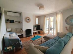 Ein Wohnzimmer mit Sofa, Fernseher und Essbereich mit Tisch.