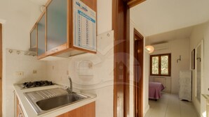 A kitchen with a gas stove, sink, and a calendar on the wall. - Aurora Celeste - Goelba (Campo nell'Elba)