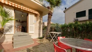 A building with a covered entrance, outdoor seating, and a palm tree. - Aurora Celeste - Goelba (Campo nell'Elba)