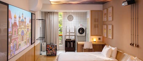 A hotel room with two beds, a large painting, a ceiling with a leaf design, a washing machine, and a suitcase.