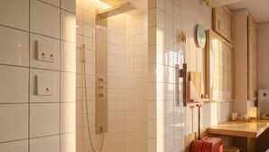 Ein modernes Badezimmer mit Dusche, Waschbecken, Spiegel und einem roten Koffer.