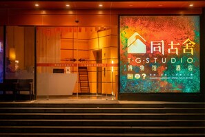 A hotel entrance with a large digital sign displaying the name 'TG STUDIO' and some Chinese characters. There are directional signs for 'AUTO DOOR' and 'AUTO DOOR 2'. - T.G.S. Museum Hotel (Guangzhou)