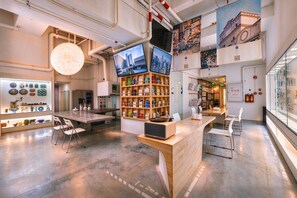A modern interior with a central wooden counter, multiple screens, and a display of various items. - T.G.S. Museum Hotel (Guangzhou)