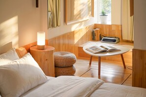 A modern bedroom with a bed, a bedside lamp, a round table with a book, a small radio, and a window with curtains. - T.G.S. Museum Hotel (Guangzhou)