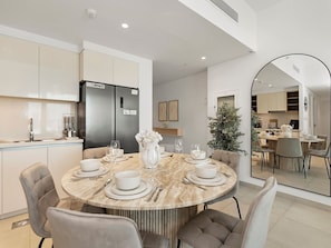 A modern kitchen with a built-in refrigerator, a dining area with a marble table, and a large mirror reflecting the space. - 2-bedroom apartment in Dubai, near Dubai mall, Burj Khalifa and Fountains (Dubai)