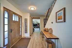 A hallway with a wooden door, a welcome sign, a staircase, and a bench with decorative items. - Piñon Peak Retreat |Hot Tub |Views |2 Living Areas (Buena Vista)