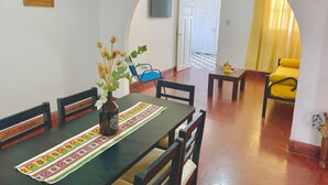 A dining area with a table set for four, a vase with dried flowers, and a blue chair. - Colonial Apt for 7 · Private Terrace · 3 Bedrooms · 9 Blocks from Main Square (Salta)