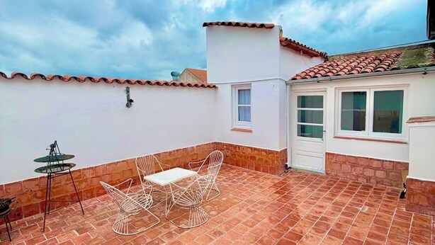 A rooftop patio with a tiled floor, a white table with chairs, and a small table with a chair. - Colonial Apt for 7 · Private Terrace · 3 Bedrooms · 9 Blocks from Main Square (Salta)