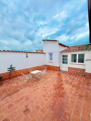 A rooftop patio with a tiled floor, a white table with chairs, and a small table with a chair. - Colonial Apt for 7 · Private Terrace · 3 Bedrooms · 9 Blocks from Main Square (Salta)