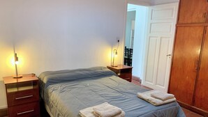 A bedroom with a bed, two bedside tables, a wardrobe, and a mirror. - Colonial Apt for 7 · Private Terrace · 3 Bedrooms · 9 Blocks from Main Square (Salta)