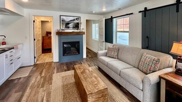 A living room with a sofa, a coffee table, a fireplace, and a sliding door. - TTStop’s Close to Yellowstone, Fireplace (Island Park)