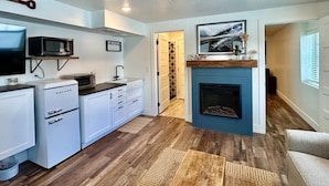 A compact living space with a kitchenette, a fireplace, and a hallway leading to another room. - TTStop’s Close to Yellowstone, Fireplace (Island Park)