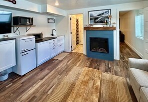 A compact living space with a kitchenette, a fireplace, and a hallway leading to another room. - TTStop’s Close to Yellowstone, Fireplace (Island Park)