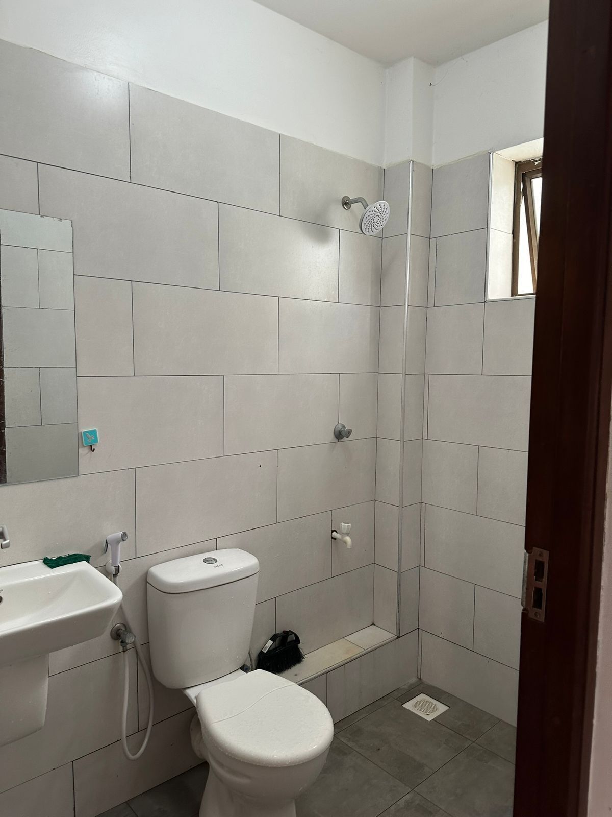 Casa de banho com sanita, lavatório e chuveiro.