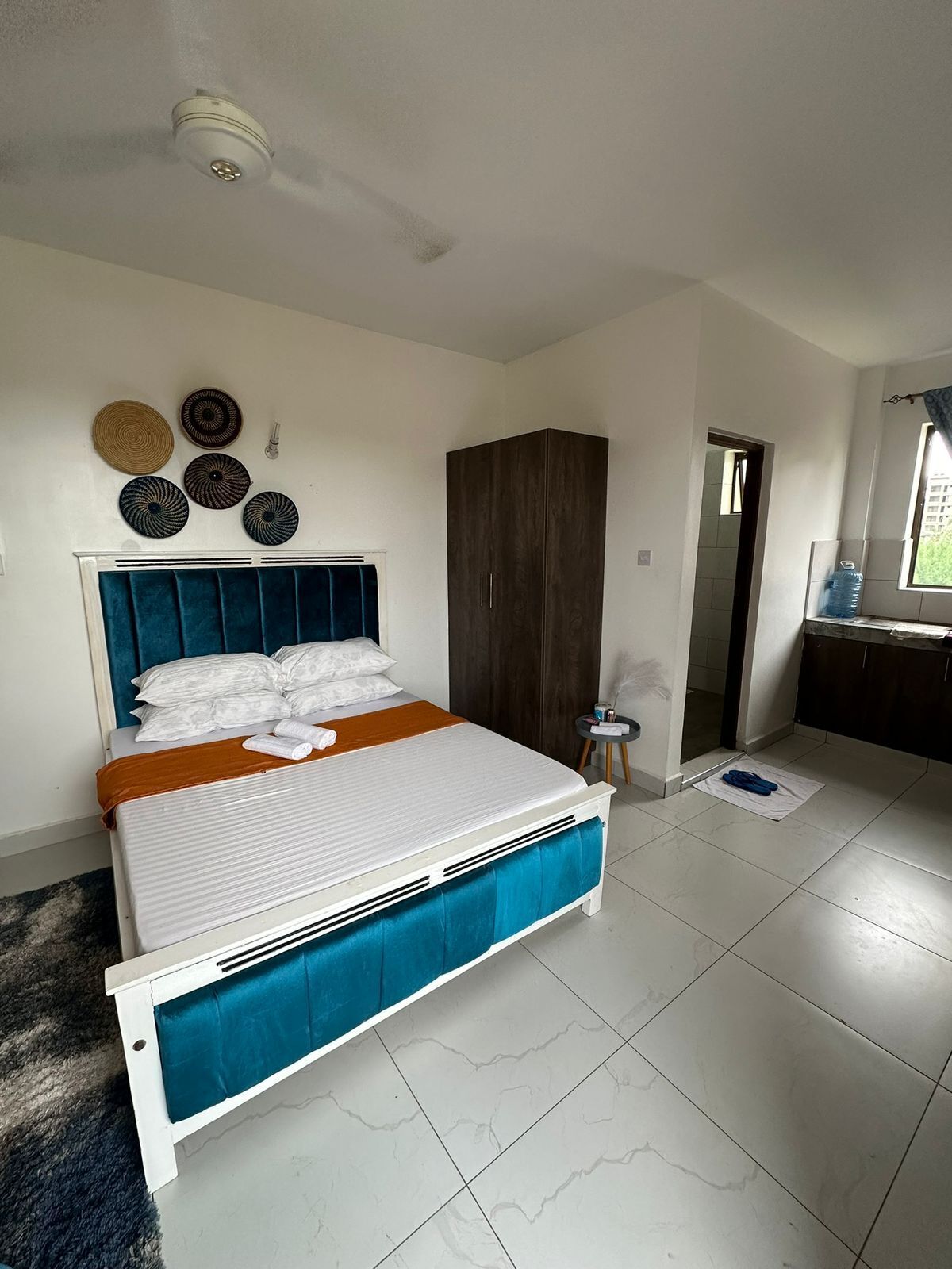 A bedroom with a bed, a wardrobe, a ceiling fan, and a window.