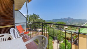 Un balcon donnant sur un paysage montagneux, une table avec des chaises et une balustrade.